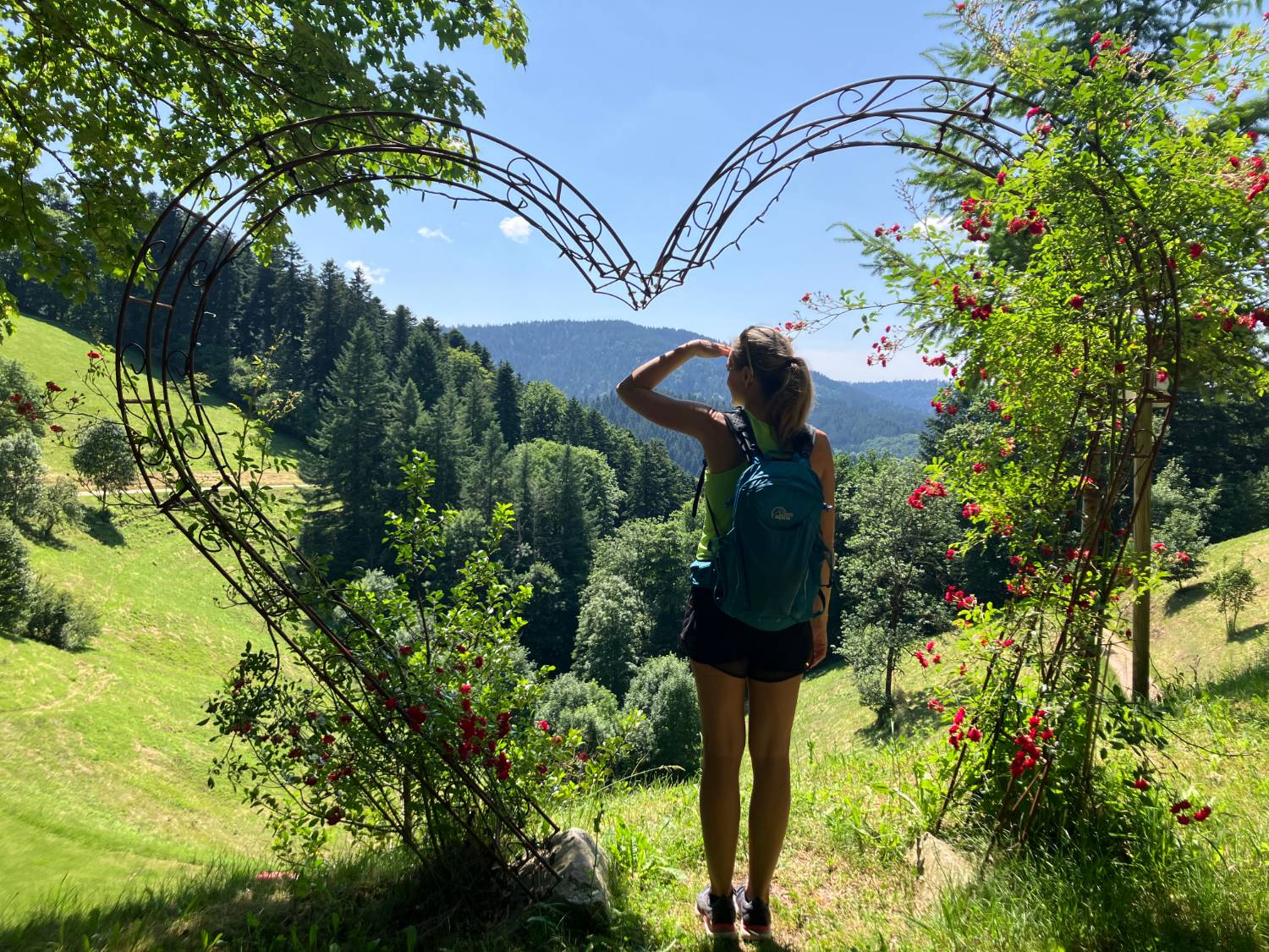 Nicole Bühler blickt durch ein herzförmiges Tor auf die Landschaft